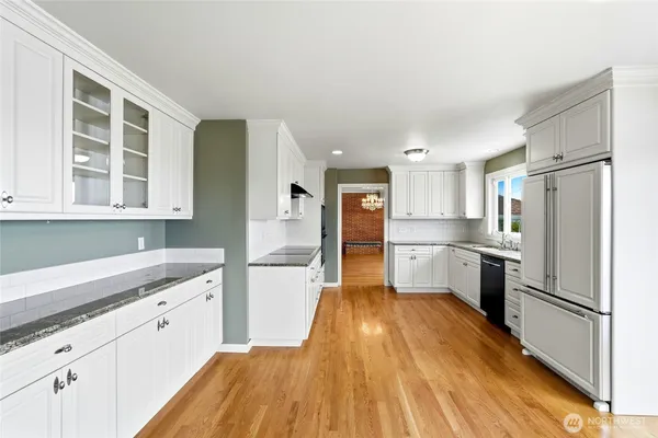a kitchen with stainless steel appliances granite countertop a refrigerator sink and white cabinets