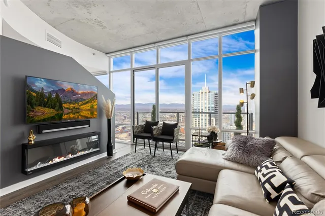 a living room with furniture floor to ceiling window and a flat screen tv