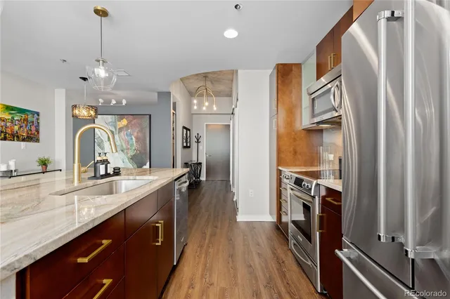 a kitchen with stainless steel appliances granite countertop a refrigerator a sink dishwasher a stove and white countertops with wooden floor