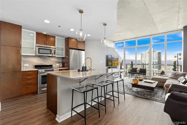 a kitchen with stainless steel appliances granite countertop a stove a refrigerator a kitchen island a dining table and chairs with wooden floor