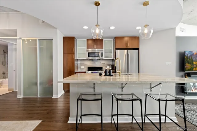 a kitchen with kitchen island granite countertop a table chairs refrigerator and microwave