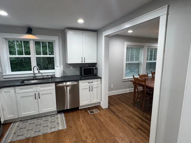 a open kitchen with granite countertop white cabinets and black stainless steel appliances