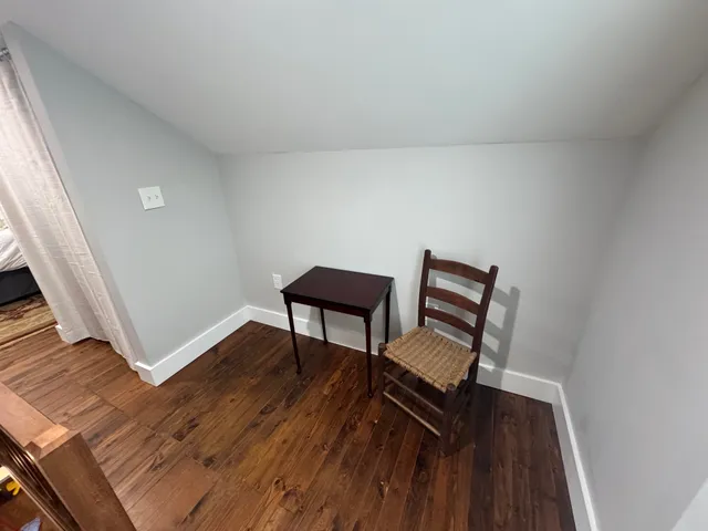 a view of a livingroom with wooden floor and a bench