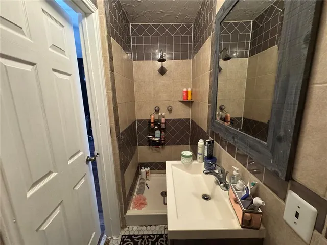 a bathroom with sink shower and mirror