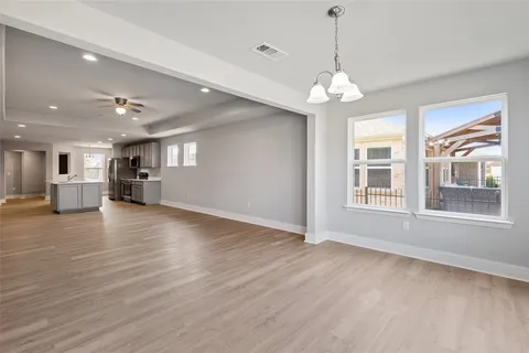 an empty room with kitchen and chandelier fan