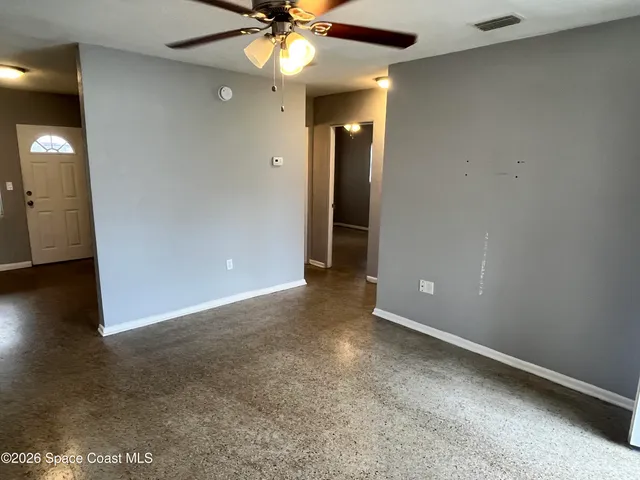 an empty room with wooden floor fan and windows