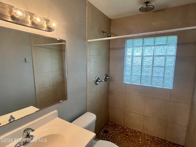 a bathroom with a sink a toilet a window and shower