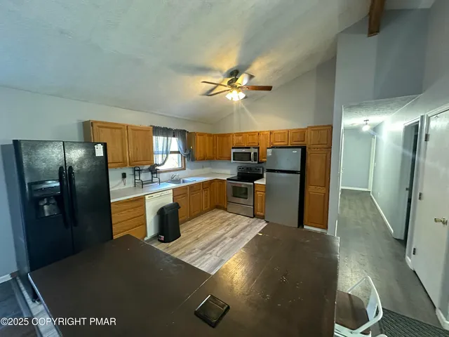 a kitchen with stainless steel appliances kitchen island granite countertop a refrigerator a stove and a sink