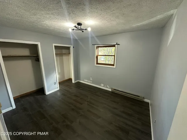 an empty room with wooden floor chandelier and windows
