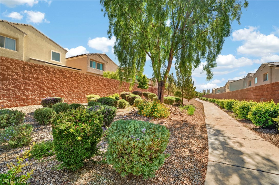 6281 Angora Peak Lane Las Vegas, NV 89115 - Photo 33 of 34 A winding pathway leads through drought-tolerant landscaping and vibrant shrubs under a vast, open sky.