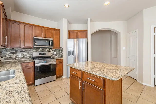 a kitchen with stainless steel appliances granite countertop a stove a sink and a microwave
