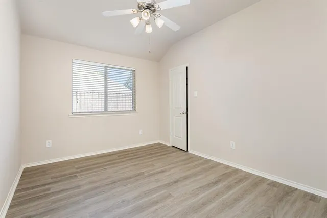 an empty room with wooden floor closet and windows