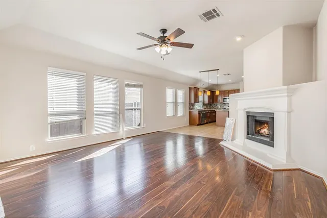 an empty room with wooden floor fireplace and windows