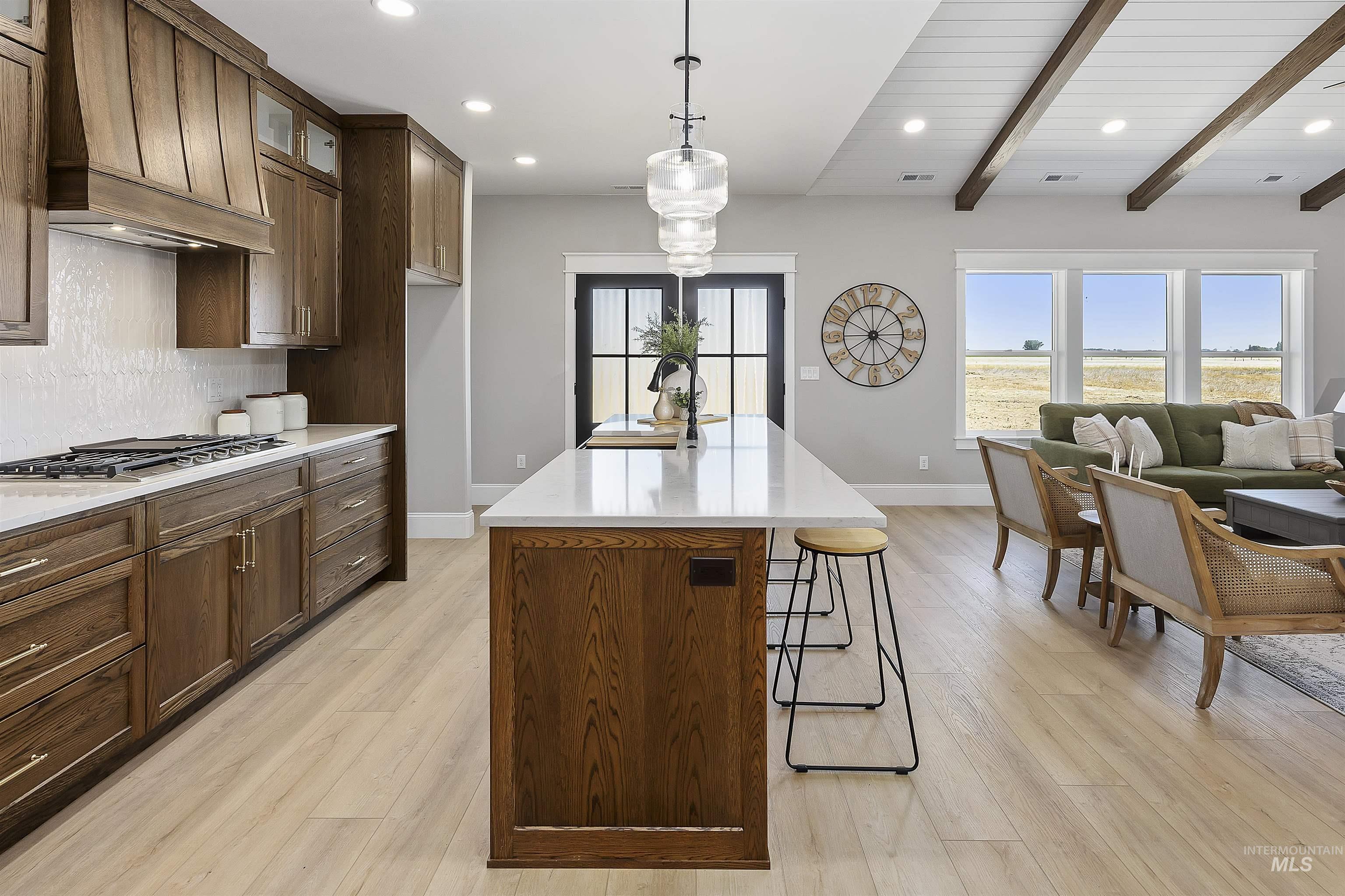 378 West 100 South Rupert, ID 83350 - Photo 13 of 50 Open-concept kitchen and living area featuring a large center island with a light-toned countertop, wood-finish flooring, dark wood cabinetry, a tiled backsplash, and recessed lighting