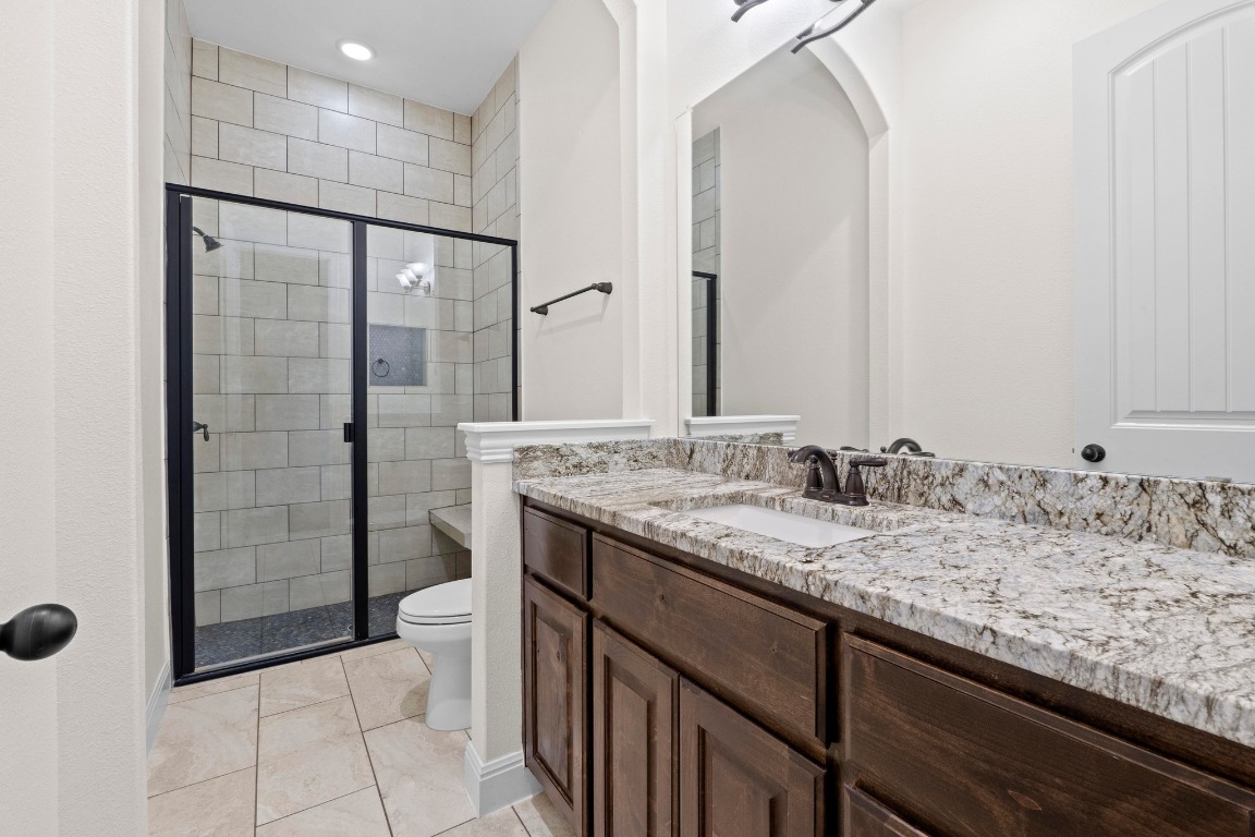 200 Tate Lane Round Rock, TX 78665 - Photo 28 of 40 a bathroom with a granite countertop sink a toilet and shower