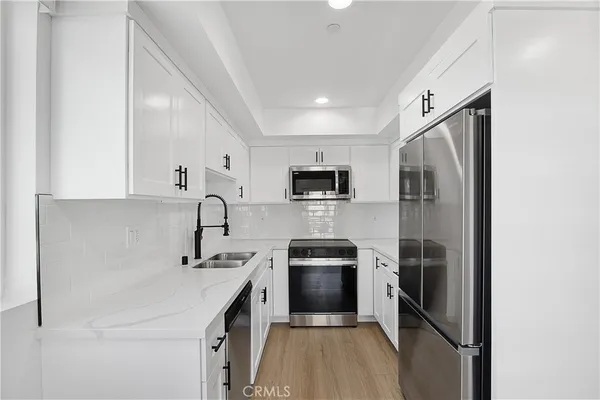 an empty room with wooden floor kitchen view and a window