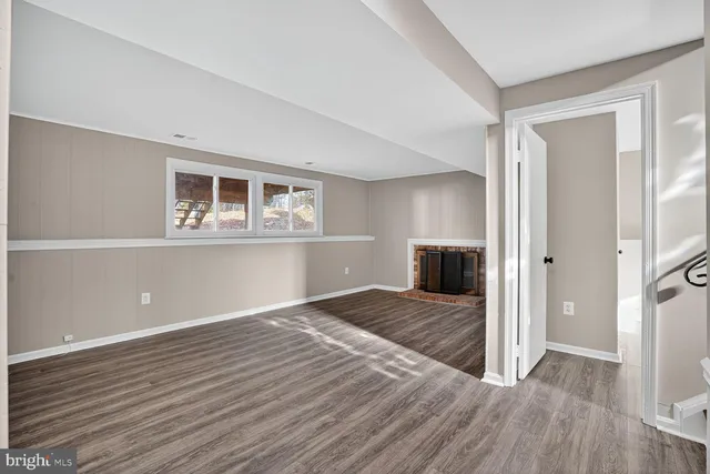 a view of empty room with wooden floor and fireplace