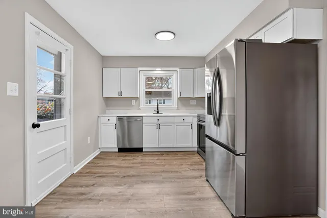 a kitchen with a refrigerator a sink and dishwasher with wooden floors