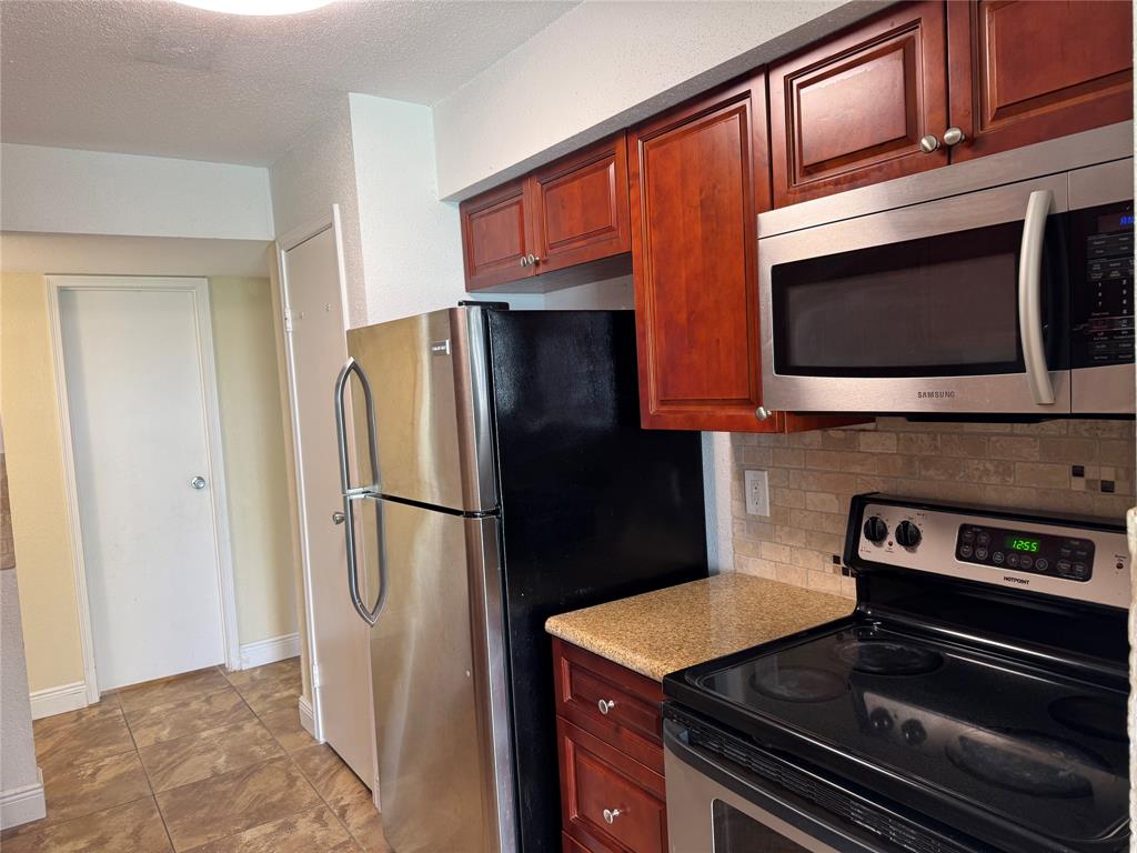 805 Riverside Drive, Unit 1112 Coral Springs, FL 33071 - Photo 3 of 26 a kitchen with stainless steel appliances a refrigerator a stove a microwave and cabinets