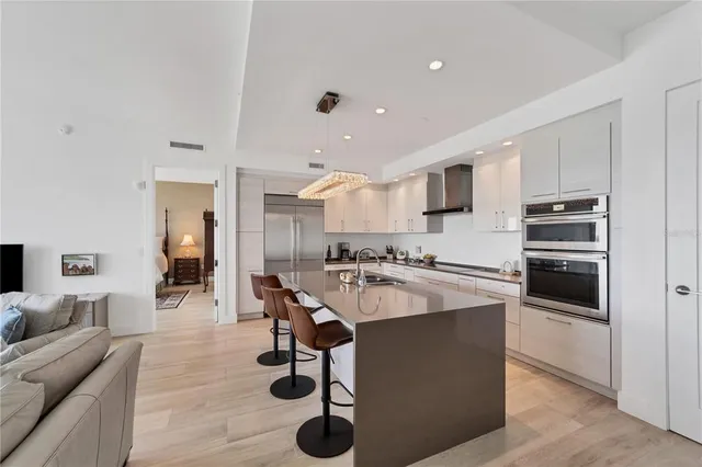 a large kitchen with kitchen island a stove a sink a refrigerator and chairs