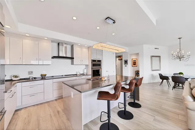 a kitchen with stainless steel appliances granite countertop a stove top oven a sink a dining table and chairs with wooden floor