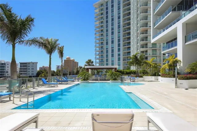 a view of a swimming pool with a lounge chair and palm trees