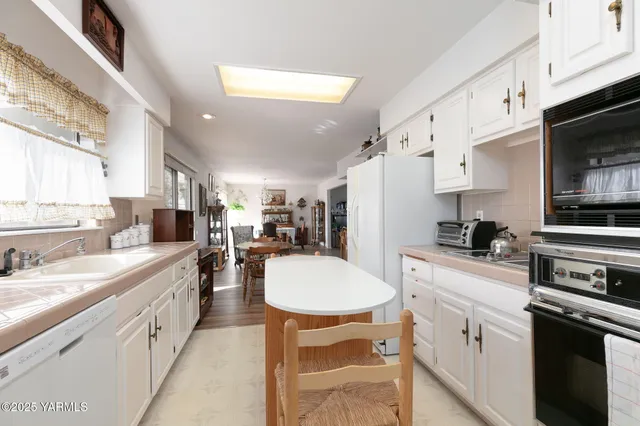 a kitchen with stainless steel appliances a stove a sink a stove a microwave a refrigerator a stove with white cabinets and wooden floor