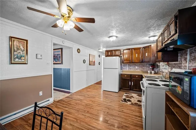 a kitchen with stainless steel appliances granite countertop a refrigerator a stove top oven a chimney cabinets and wooden floor