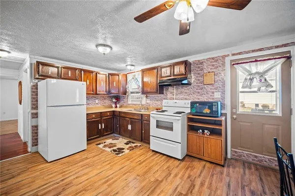 a kitchen with a refrigerator a stove top oven a sink dishwasher and white cabinets with wooden floor
