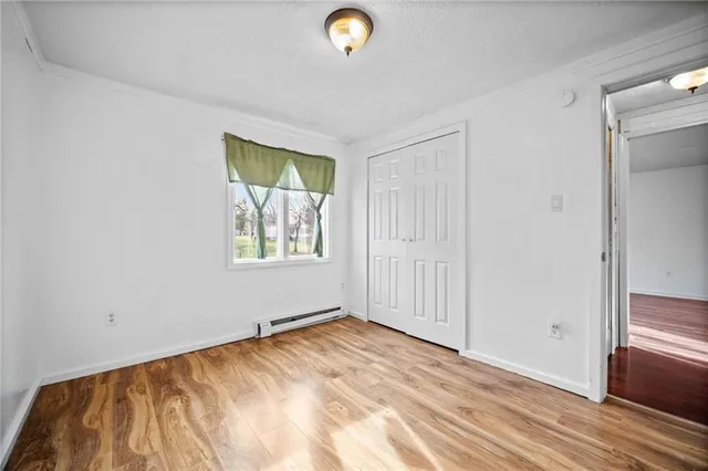 a view of an empty room with window and wooden floor