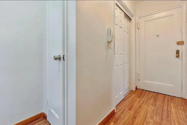 a view of a hallway with wooden floor and closet