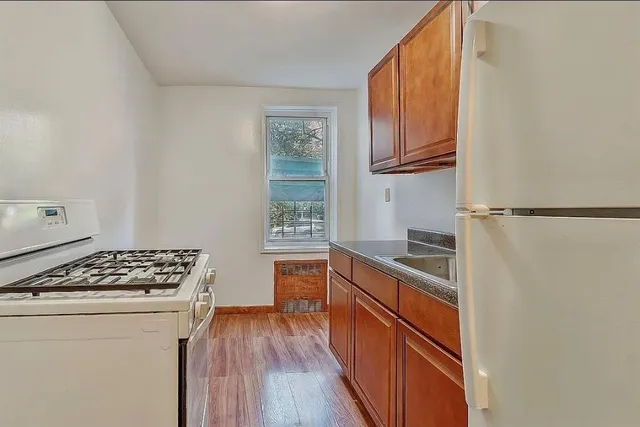 a kitchen with stainless steel appliances granite countertop a stove a sink dishwasher and wooden cabinets with wooden floor