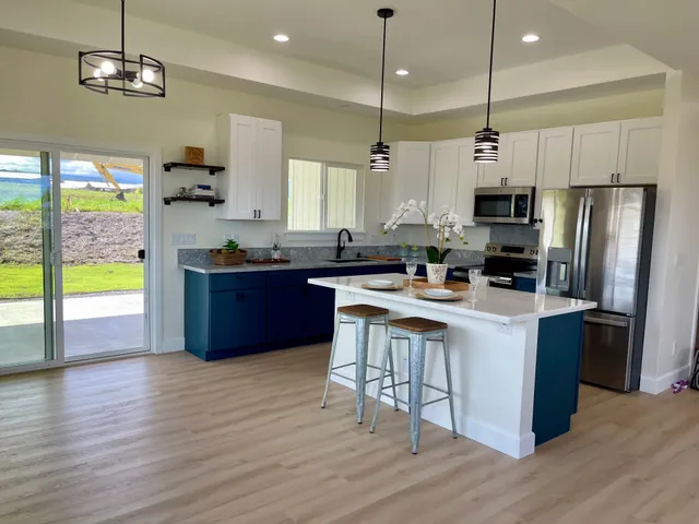 a kitchen with stainless steel appliances granite countertop wooden floors a stove a sink and a refrigerator