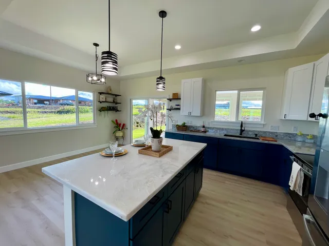a kitchen with kitchen island granite countertop a sink a counter space appliances and cabinets