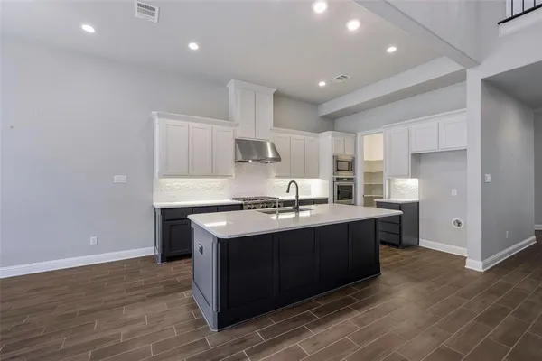a kitchen with kitchen island granite countertop a sink cabinets and stainless steel appliances