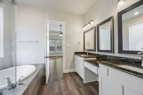 a bathroom with a granite countertop sink and a bathtub
