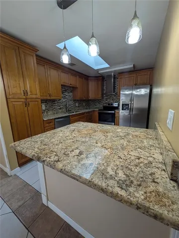 a kitchen with stainless steel appliances granite countertop a sink a stove and a refrigerator