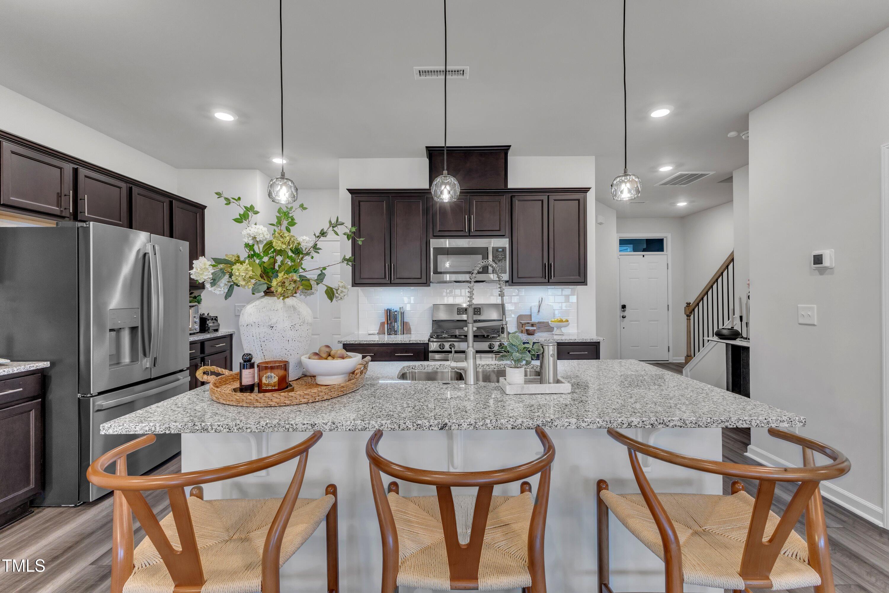 5814 Empathy Lane Raleigh, NC 27616 - Photo 12 of 48 a kitchen with stainless steel appliances granite countertop a refrigerator a sink a stove a dining table and chairs