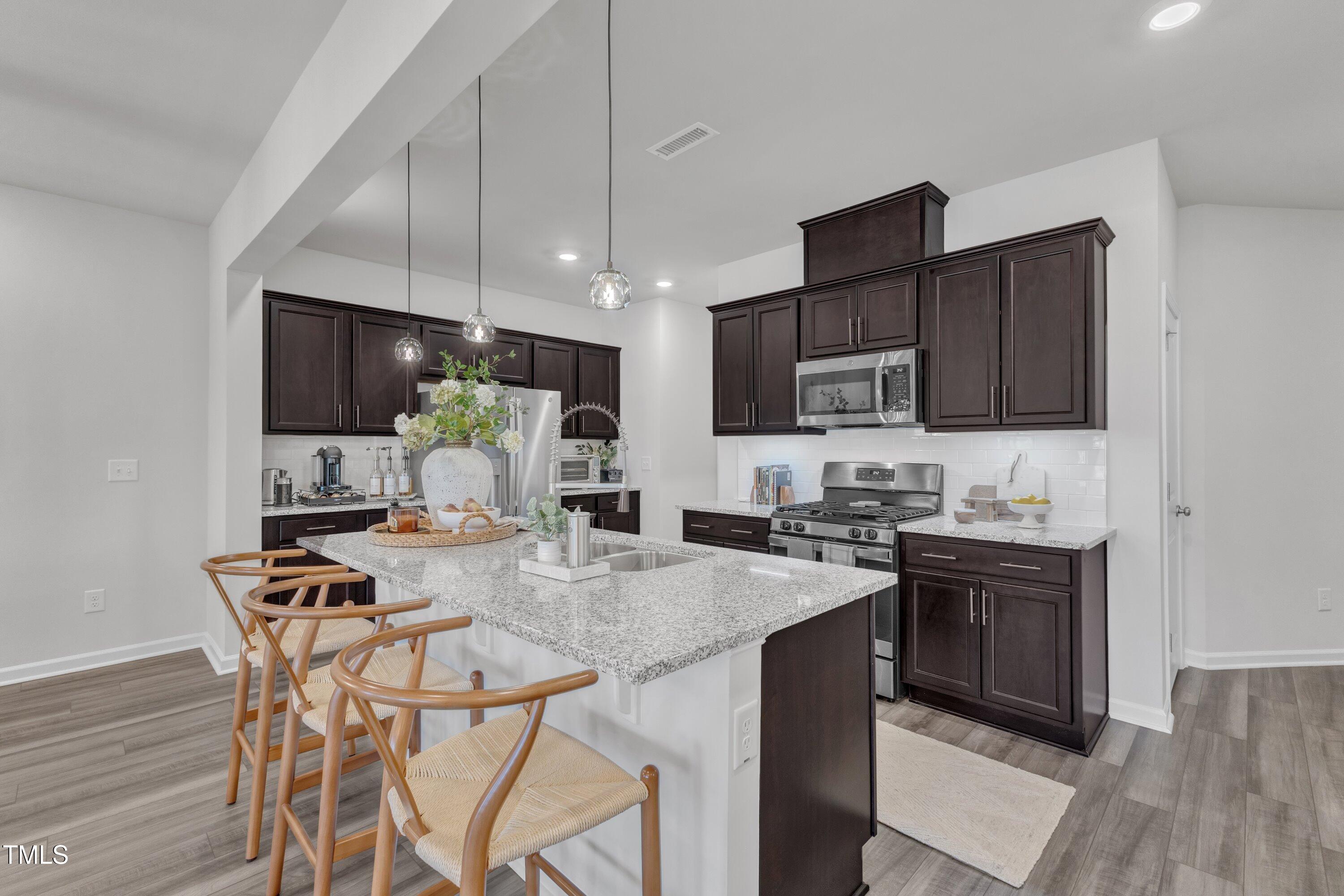 5814 Empathy Lane Raleigh, NC 27616 - Photo 13 of 48 a kitchen with stainless steel appliances granite countertop a stove top oven a sink dishwasher a dining table and chairs with wooden floor