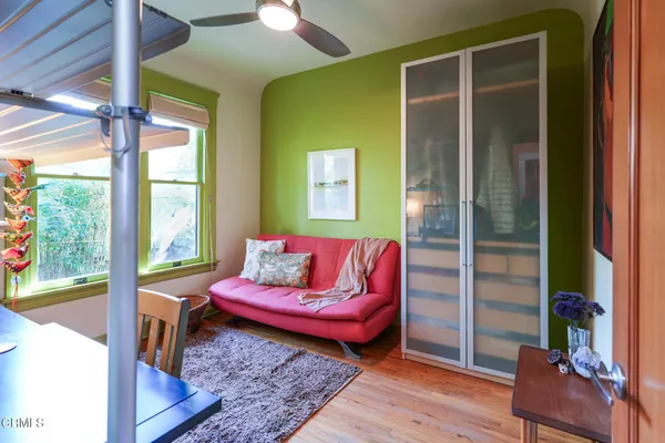 a bedroom with furniture large window and wooden floor