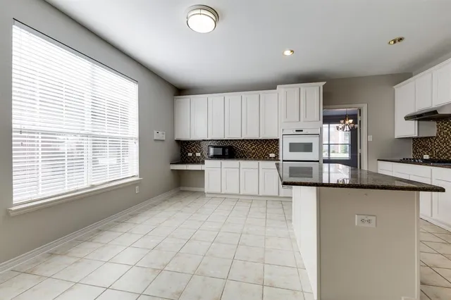 a kitchen with granite countertop a stove a sink and a refrigerator
