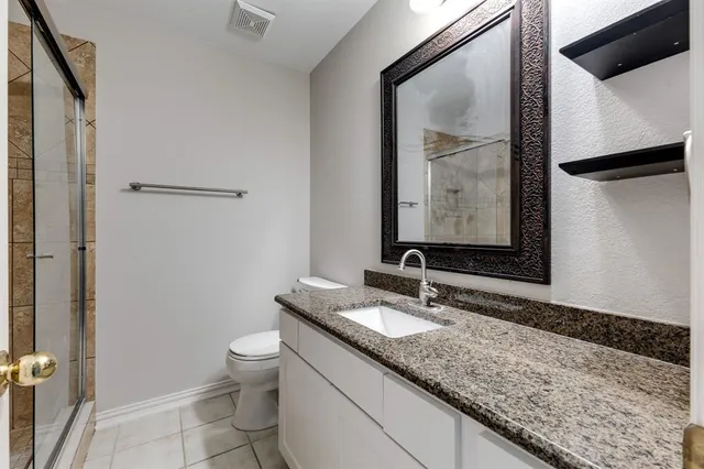 a bathroom with a granite countertop sink toilet and mirror