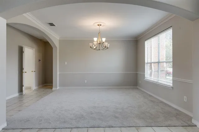 an empty room with chandelier and windows