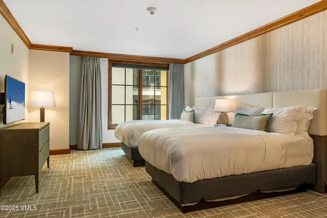 a bedroom with a bed lamp on desk and a window