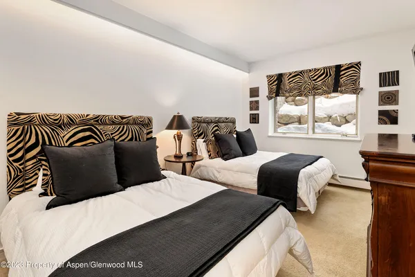 a bedroom with two beds and a large mirror next to a window