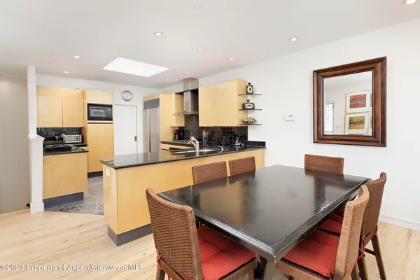 a kitchen with stainless steel appliances granite countertop a stove a sink a dining table and chairs