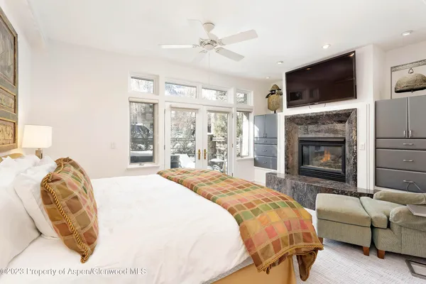 a spacious bedroom with a bed a fireplace and a flat screen tv