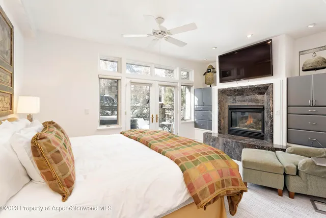 a spacious bedroom with a bed a fireplace and a flat screen tv