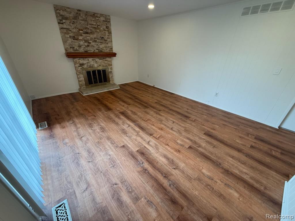 28144 Yorktown Road Farmington, MI 48331 - Photo 5 of 25 Spacious room featuring wood-finish flooring, a stone-clad fireplace with a wood mantle, and white paneled walls