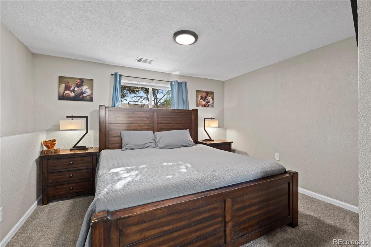 205 Walnut Street Frederick, CO 80530 - Photo 14 of 31 a bedroom with a bed and a lamp on dresser